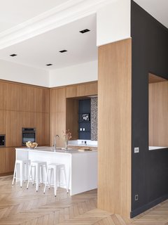 Designed by Hermand, the made-to-measure Oberflex kitchen anchors the semi-open layout. The kitchen island has been varnished in Farrow & Ball's strong white and features a Silestone Blanco countertop and stools from Tolix. The terrazzo backslash is from Carrément Victoire. 