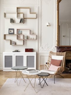 Traditional features such as the high ceilings, decorative moldings, and parquet flooring take on a softer, modern tone when set against a contemporary selection of furniture. The walls have been painted in the strong white shade from Farrow & Ball. The shelving is by Dédal by Matégot and the armchair is from Redoute. 