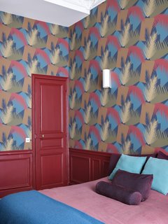 Bold choices for the guest room include Cole & Son's Deco Palm Wallpaper in red and blue.