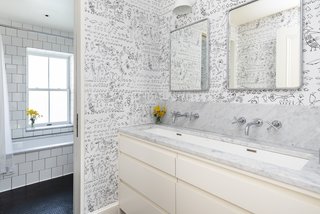 The fourth-floor hall bathroom has double faucets over a large trough sink, a custom vanity, and black penny-round tiled floors. A pocket door separates the sink area from the tub and toilet.