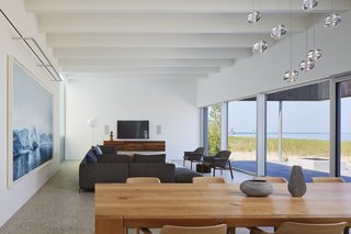 The open-plan living and dining area features a bright, expansive sense of space thanks to the wall of windows and the spectacular surrounding views. 