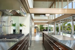 The open kitchen is bright and airy thanks to double-height ceilings, a wall of windows, and classic post-and-beam construction. 