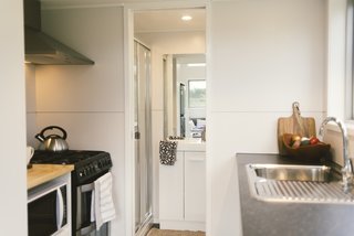 The efficient tiny kitchen comes with a fridge, oven, and dishwasher. This room also allows for access to the bathroom, which includes a shower and a composting toilet. 