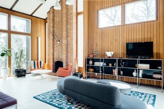 High ceilings and a full-length brick fireplace are complemented by extensive glazing. 