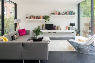 The living room is bright and airy thanks to floor-to-ceiling glazing and a crisp white wall. 