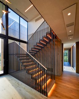 A double-height entryway features both stairs and an elevator which lead to the elevated main level. The stairway design echoes the exterior siding. 