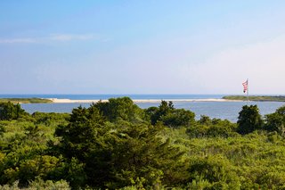 The view overlooks a glistening pond and the Atlantic Ocean beyond. 
