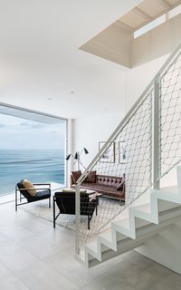  A central staircase with perforated metal treads and risers allows natural light to filter down from the roof-deck level through the center of the home. 