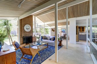 The open living/dining/kitchen area features a wall of glass, post-and-beam vaulted ceilings, Eichler's signature brick fireplace, as well as radiant floor heating throughout.
