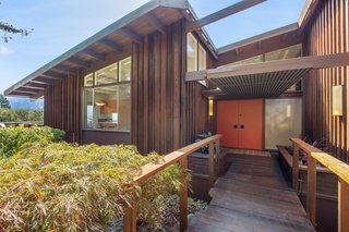 The entry of the wood-clad property features beautiful midcentury lines. 