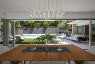Glass doors open wide, leading to the expansive outdoor space which features a pool, spa, and fire pit.