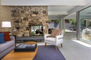 A two-sided stone fireplace divides the living room area.