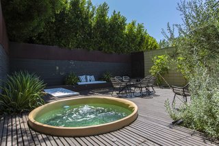 A jacuzzi is tucked away in the back corner of the yard.