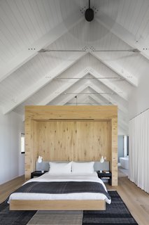 The master bedroom features vaulted ceilings and a light-wood wall to break up the space. 