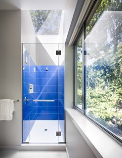  A bright bathroom is surrounded by tree views. 