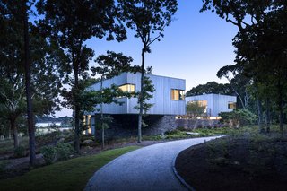 The home's siting marks a transition from the trees to the rolling fields that extend out to the distant waterfront. 