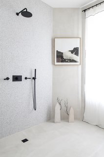 Even the terrazzo and concrete black-accented bathroom is a stunning showcase for the collection. The shower has been left open since it will not be used. 