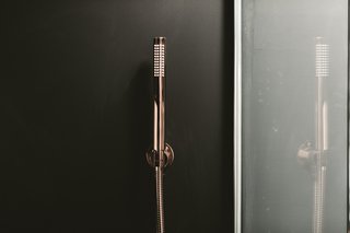 The interiors of the ensuite bathroom contrast dark colors with elegant copper Lusso fixtures. 