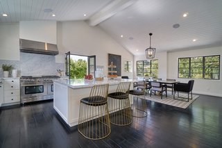 The open chef’s kitchen boasts Carrara marble countertops, Viking appliances, and flows into a light-infused dining area. 