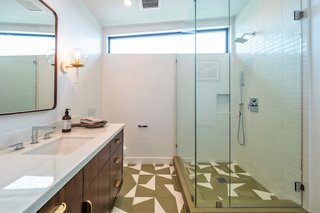 Graphic floor tiles, wood, and brass give the bathroom a polished, retro vibe.