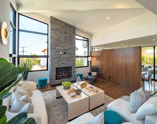 A step-up family room features a soaring, 16-foot, beamed ceiling with expansive glazing and a dramatic stone fireplace. 