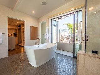 The large ensuite master bath opens to a balcony which has an outdoor shower and a green wall for privacy. High-end touches include wall-to-wall tiling, a steam shower, a freestanding soaking tub, and a Toto Neorest bidet toilet.