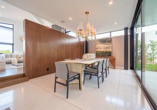 A floating walnut wall separates the space from the formal dining area, which overlooks and opens to the outdoor space.