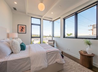 Globe pendant lighting and a beamed ceiling give this bedroom a midcentury feel. 