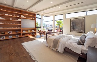 The master suite is bright and airy with floor-to-ceiling windows, a beamed ceiling, built-in teak bookshelves, and an oversized walk-in closet with LED lighting.