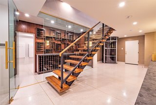 A temperature-controlled, glass-enclosed wine room with custom display shelving sits next to a large laundry facility with a pet shower. 
