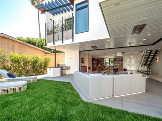 Outside, the lush landscaping includes palm trees and drought-tolerant succulents. The rear yard is prepped for a swimming pool and has a flat, grassy area with a hedge of trees for privacy.