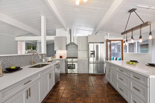 The updated chef’s kitchen features new stone countertops, as well as a stylish backsplash, a large island, and stainless steel appliances. 