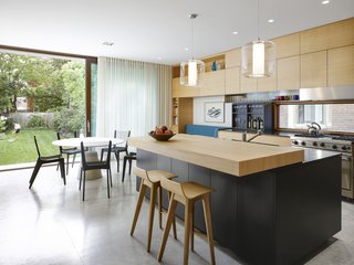 A look at the spacious eating area, office nook, and a bespoke built-in daybed, completed with a reading light. Large doors open the space to the outdoors for integrated indoor/outdoor living during the warmer months.
