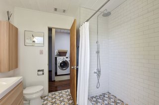 The spacious master ensuite bath has been remodeled with new tile, cabinetry, and fixtures. 