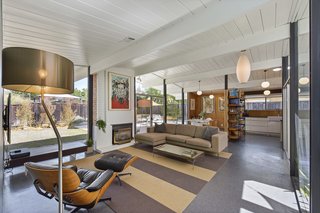 The vaulted tongue-and-groove ceiling and brick fireplace have both been painted white, a choice that further brightens the open-plan living space. 