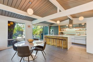 The kitchen opens to the living area, which has a recessed gas-flame fireplace and new full-height glass walls and sliding doors. 