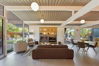 The post-and-beam construction is highlighted by the use of white paint against the ceiling's natural wood finish, creating a chic, modern look. 