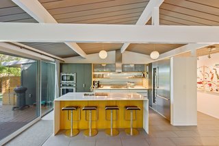 The open kitchen features bespoke cabinetry, quartz counters, built-in Thermador appliances, a full-size wine fridge, a gas cooktop, and a breakfast island with cleverly hidden electrical outlets. 