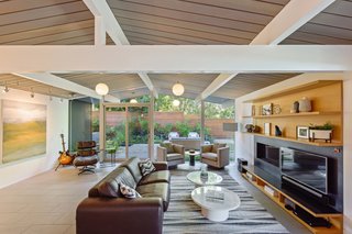 The open-plan living room features expanses of glass, integrating the lush surroundings into the bright and airy space. 