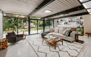 The open-plan living room features a wall of glass with sliding doors that lead out to a pool. 