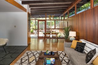 The living room is capped by a dining area at the other end, where another wall of glass opens to the other side of the home, creating the potential for lovely cross breezes. 