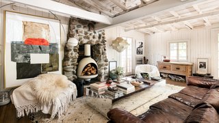 The cozy living room has a modern bohemian sense of style but is still firmly anchored to the home's past through the stone inlay hearth.