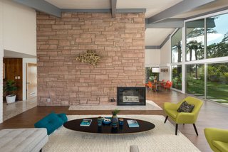 The open-plan living space is anchored by a grand dual-sided fireplace. Extensive glazing brings a strong sense of the outdoors in and keeps the interiors bright and airy.