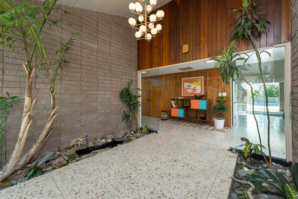 The stunning interiors feature an authentic midcentury-modern material palette that includes original terrazzo flooring, brick, and warm wood paneling.