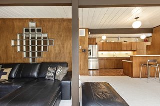 Classic midcentury features such as wood paneling, globe pendant lighting, and beams appear throughout the home. 