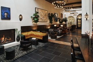 A highly curated collection of artwork adorns the vibrant lobby, which is richly textured with dark woods, lush jewel-toned velvets, brass, and leather. A work by Jesse Mockrin hangs above the hearth. 