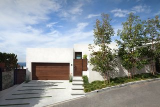The hillside house appears to be single-story in the front, but it actually comprises multiple levels. The garage door, gates, and mailbox are made from stained cedar that ties in with the siding on the back of the house. 