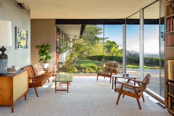 The midcentury modern home features wraparound glass walls.