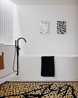 A bold black and white bathroom with a graphic leopard print rug. 