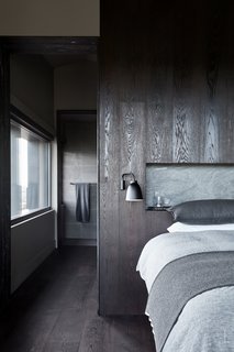 The minimalist material palette incorporates light and shadows into a tonal, textural mix. The dark flooring and paneling are both Nero Oak Volcano from Mafi. 